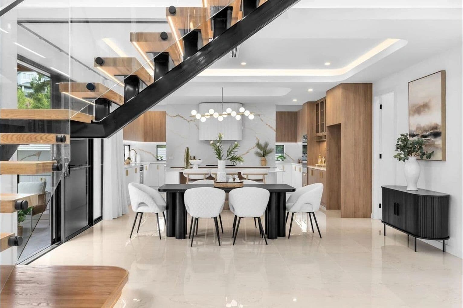Modern kitchen and dining area styled by RitZi Stagings with a floating marble staircase.